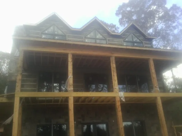 Dormers and porch framing on a large log home under construction — Roof Coating work by our crew in Rock Rapids