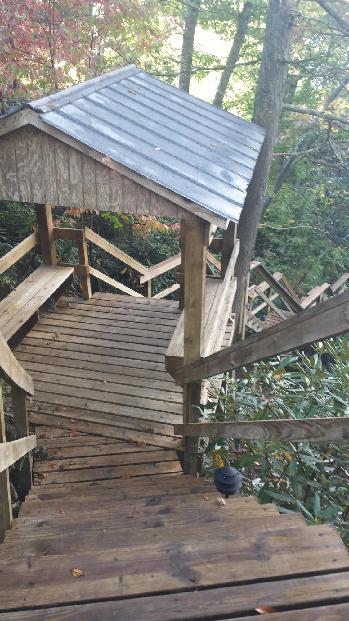 Metal roofed shelter over wooden steps on a wooded walkway — Skylight Repair & Installation work by our crew in Rock Rapids