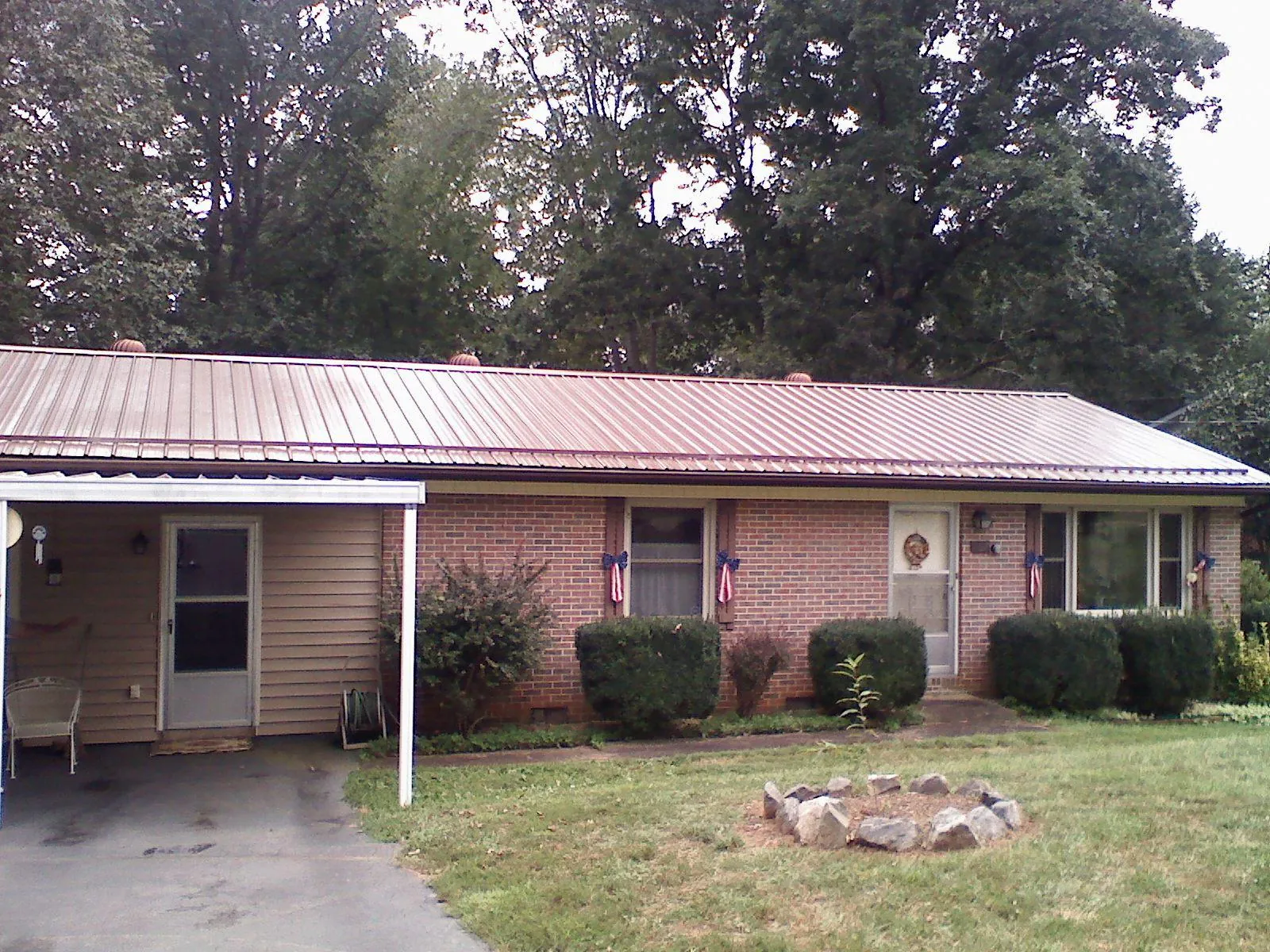 Bronze metal roof and carport on a brick ranch home — Roof Repair work by our crew in Rock Rapids
