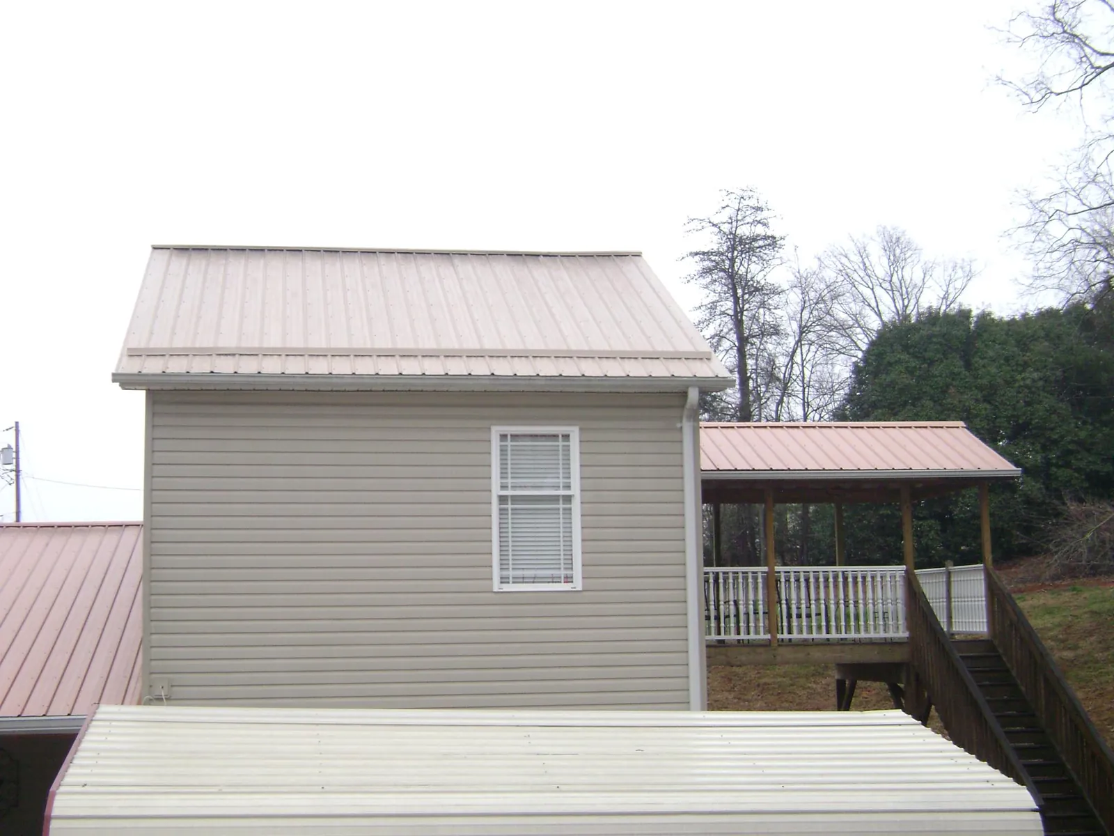 Tan metal roofs on a two story addition and attached porch, from a Roof Replacement job in Rock Rapids