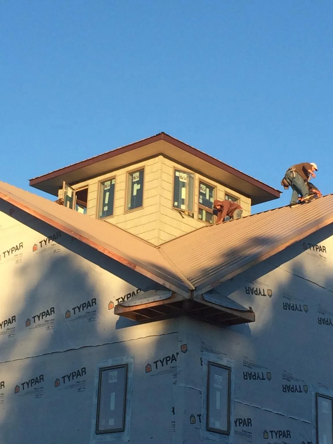 Roofers working around a rooftop cupola on a new metal roof at sunset — Roof Waterproofing in Rock Rapids by Roofing Brothers